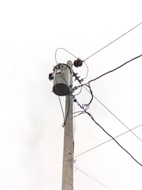 Seçici odaklanma. Kablolar ve diğer bağlantı ekipmanlarıyla bir elektrik direği Endonezya 'da açık bir gökyüzüne karşı duruyor.