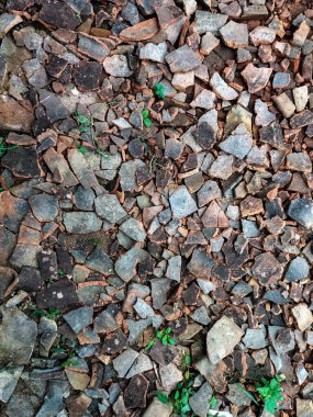 Kırık çatı fayanslarının yakın görüntüsü yollarda kullanılan çakıllarla harmanlanmış. Endonezya.