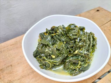 Seçici odaklanma. Daun singkong ya da Cassava yaprağı körisi, Hindistan cevizi sütü ve baharatlı baharatlı haşlanmış kaju yapraklarından yapılan geleneksel bir Endonezya yemeğidir.. 