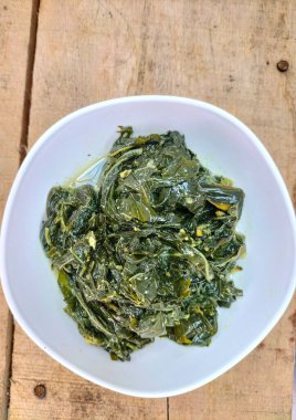 Seçici odaklanma. Daun singkong ya da Cassava yaprağı körisi, Hindistan cevizi sütü ve baharatlı baharatlı haşlanmış kaju yapraklarından yapılan geleneksel bir Endonezya yemeğidir.. 