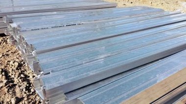 Yığılmış kare boruların görüntüsü. Toprakta bir sürü çelik parçası var. Üretim. Paslanmaz çelik.