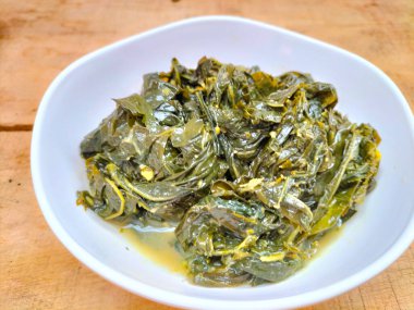 Seçici odaklanma. Endonezyalıların en sevdiği yemek. Cassava yaprağı körisi, hindistan cevizi sütü, zerdeçal, domates, acı biber ve diğer baharat ve otlarla birlikte pişirildiğinde yapılır..