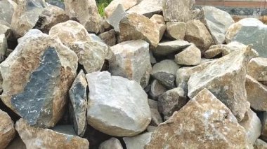 Güneş ışığındaki büyük taş yığınının görüntüsü pürüzlü dokularını ve pürüzlü yüzeylerini gösteriyor. Taş arkaplan. 