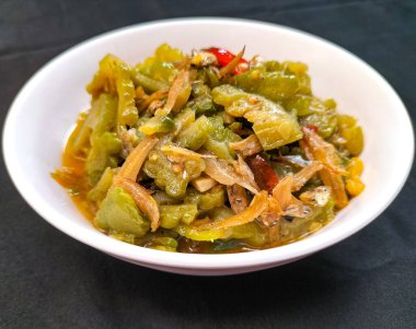 Yakın çekimde kızarmış kavun ya da acı biberli Pare ve beyaz kasede soğan. Siyah arka plan. Tipik bir Endonezya sebze yemeği..