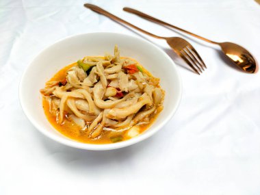 Seçici odaklanma. Karıştırılmış istiridye mantarı ya da midye reçeli tiram. Tadı daha taze olsun diye domatesle servis ediliyor ve beyaz arka planlı beyaz bir kasede servis ediliyor. Kaşık ve çatal..