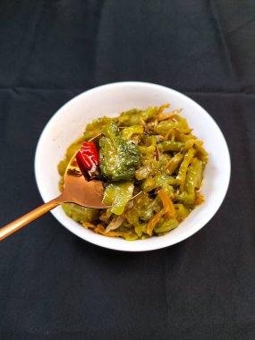 Kızarmış kavun ve ançüezli, siyah arka planda beyaz bir kasede servis ediliyor. Bu kavrulmuş kavunun lezzetli bir tadı var. Acı kavundan biraz baharatlı ve acı.. 