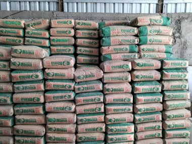 İnşaat malzemeleri dükkanında çeşitli markalardan yığınla çimento. Malzeme ticareti konsepti. Çimento çuvalları bir depoda saklanır.. 