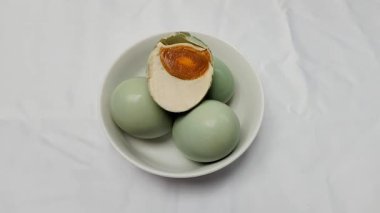 Görüntü. Tuzlu mavi ördek yumurtaları beyaz bir kaseye yerleştirilir. Tuzlu ördek yumurtası işlenmiş yiyecek. Tuz ile korunan yumurtalardan yapılan yemekler.