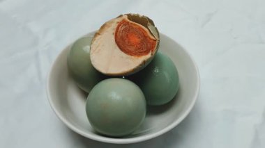 Görüntü. Tuzlu mavi ördek yumurtaları beyaz bir kaseye yerleştirilir. Tuzlu ördek yumurtası işlenmiş yiyecek. Tuz ile korunan yumurtalardan yapılan yemekler.