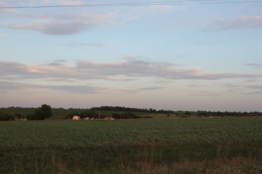 Köyün eteklerinde mavi gökyüzü ve tarlası olan bir manzara.