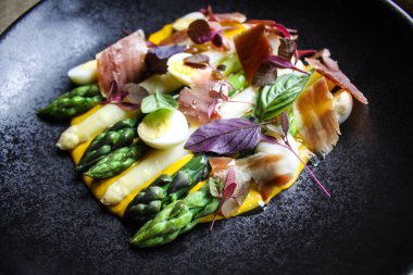 Fine dining style dish with asparagus, bechamel, cured ham and quail eggs