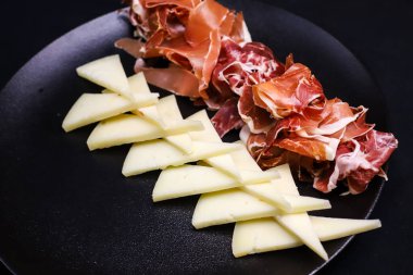 Platter of Spanish premium products cheeses- Manchego, Idiazabal, Garrotxa, hams Jamon Serrano, Jamon Bellota Joselito