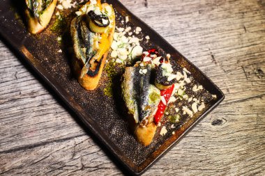 İspanyol ızgara sardalya Boquerones Romesco sosu ve bademle birlikte ekşi ekmeğin üzerinde servis edilir.