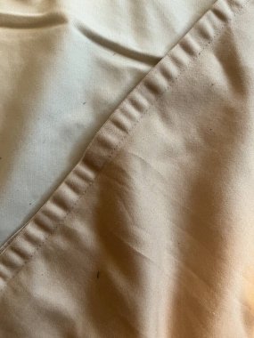 Bir açık renkli çarşaf diğerinin üzerinde yatıyor.