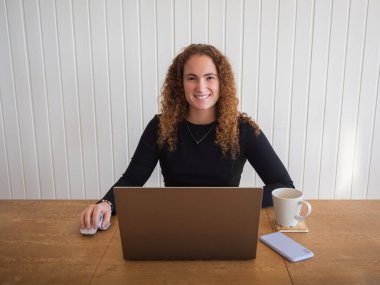 Evinden uzaktayken gülümseyen ve çay içen kızıl saçlı bir kadının ön görüntüsü.