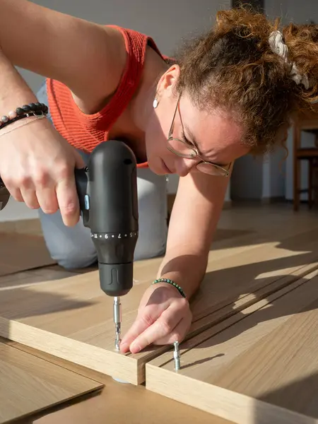 Elektrikli matkapla DIY marangozluk projesinde çalışan çalışkan bir kadının yakın çekimi.