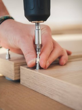 Tahta montaj için elektrikli matkap kullanan birinin elini yakalayan hassas bir yakın çekim.
