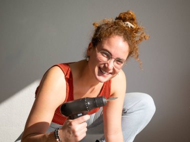 Elinde kablosuz matkap tutan gülümseyen bir kadının yakın plan çekimi. Kendin yap ev geliştirme aktivitesine girişiyor.