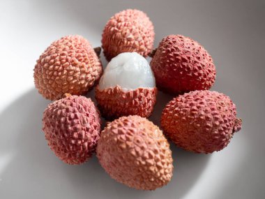 İçindeki tatlı, şeffaf beyaz eti ortaya çıkarmak için soyulmuş canlı kırmızı liçi koleksiyonu, doğal ışıkta yakalandı.