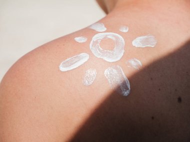 Güneş kremi sürmüş çıplak bir omuz yakın çekim, plajda güneş koruması.