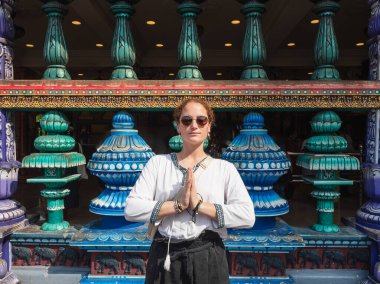 Malezya 'daki Batu Mağaraları' nın canlı ve karmaşık girişinde Namaste pozu veren bir turist kültürel saygı ve ruhani keşifte bulunuyor.