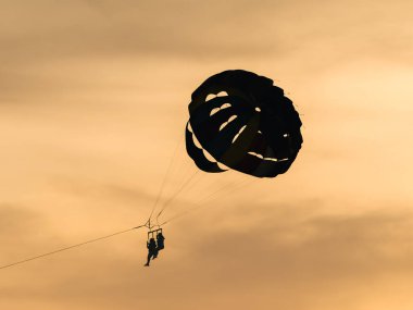 Altın bir gün batımına karşı gölgede yüzen iki insan ufkun üzerinde muhteşem bir macera ve özgürlük görüntüsü yaratıyor. Neşeli günbatımı macerası