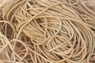 Güneşle beyazlatılmış ahşap iskelede kalın bir halat var. İpin dokusu pürüzlü ve yıpranmış, rengi kahverengi ve gri tonlarında solmuş.