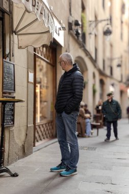 Barcelona, İspanya, Avrupa 'da bir caddede restoran tahtasına bakan yaşlı bir adam. Öğle ya da akşam yemeği vakti. Günlük kıyafetler giyiyor, bu da aktif ve sağlıklı bir yaşam tarzını gösteriyor..