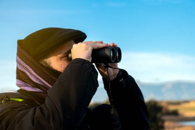 Su deposunda dürbünüyle hayvan arayan genç bir çocuğun yakın çekim görüntüsü.
