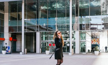 İş merkezinin dışında iş yapan bir kadın yöneticinin Amerikan çekimleri. Arka planda ofisler var..