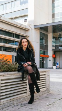 Finans merkezinin dışında akıllı telefonunu kullanan bir kız yöneticinin arka planda ofis binaları olması ihtimali çok düşük.