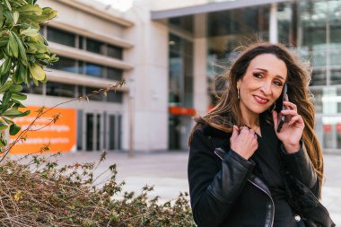 İş yerinin dışındaki yönetici kız telefonda konuşurken gülümsüyor, yakın plan.