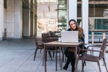 Genel olarak, yönetici bir kızın bilgisayarında yazı yazarken ve bir barın terasında iş molası sırasında kahve içerken görülüyor..