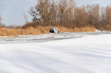 Nehirlerden geçen bir araç. Nehirden geçen büyük tekerlekleri olan bir araba. Nehri geç. Nehrin karşısında kışın SUV.