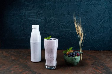 Glass with berries and mint. A glass of yogurt with gooseberries and blueberries. Wheat and berries. Front view.