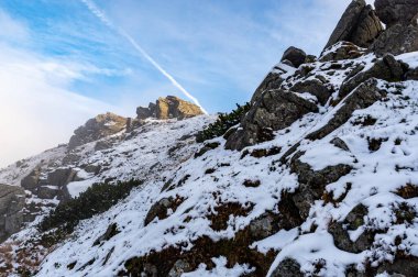 Sky view. The mountains are covered with snow. A plume in the sky from an airplane. Mountain View.