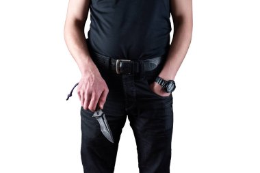 A man in black clothes with a knife in his hands. A man holds a folding knife in his hand. Man and knife on a white background. Front view.