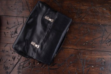 Leather briefcase with iron clasps. Black leather briefcase on the table. View from above.