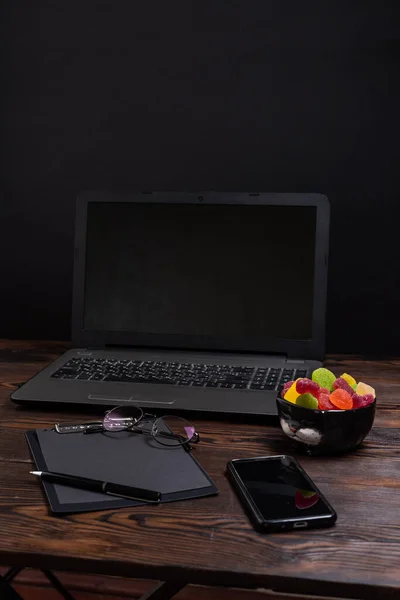 stock image Tablet for writing and laptop. Multi-colored sweets on the desktop. Pen and notebook. Workplace. Vertical frame.