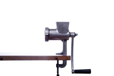 Eski bir demir et öğütücüsünün izole edilmiş hali. Klasik kıyma makinesi. Sovyet yapımı kıyma makinesi. Masanın üzerinde bir sapı olan kıyma makinesi. Ön görünüm.