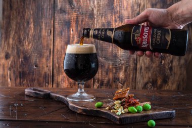 Kyiv, Ukrayna: 21 Ağustos 2022: Siyah bira Krusovice. Bardağa bira dolduruyorum. Soğuk koyu bira. Ön görünüm.