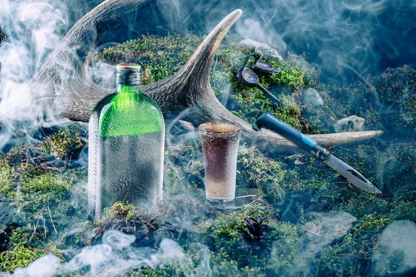 Chilled drink and glass. The bottle and glass are covered with frost. Needles and smoke. Composition of alcoholic drink. Front view.