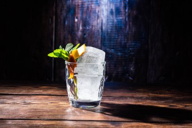 Buzlu ve baharatlı bardak. Viski bardağı. Bardakta nane ve narenciye..