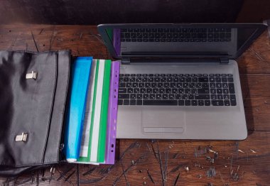 Bilgisayarı ve evrak çantasını aç. Not defterleri ve belgelerle dolu bir evrak çantası. Çalışma masası. Evraklar masada. Bir açıyla ön görünüm.