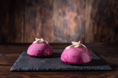 Masada iki tane pembe kek var. Narin pembe kekler ve çikolata. Ahşap arka plan. Ön görünüm.