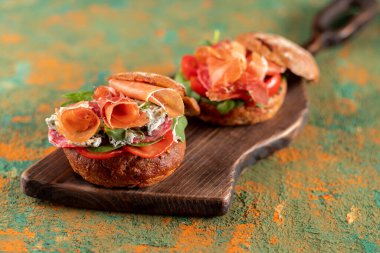 Sandviç servisi. Jambonlu ve otlu sandviçler. Kesme tahtasındaki sandviçler. Yukarıdan bir açıyla görüntüle.