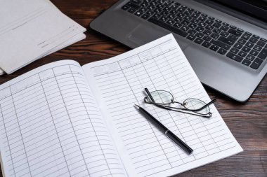 Finans ve muhasebe. İşletme. Not defterine kalem ve gözlük. Günlükte siyah kalem. İşletme. Yukarıdan görüntüle.