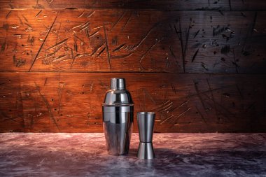 Demir karıştırıcı ve ölçü camı. Titreyen ve barmen bardağı. Kokteyl yapma seti. Tabaklar ahşap arka planda. Arkaplanda ışık huzmesi.