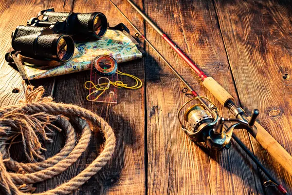 Dönen çubuk ve dürbünle balık kompozisyonu. Tahta arka planda makaralı bir olta kamışı. Yukarıdan bir açıyla görüntüle.