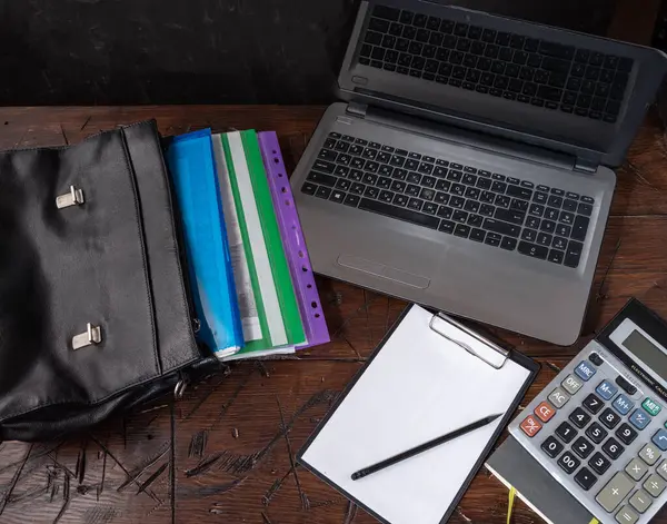 İçinde belgeler olan deri bir çanta. Belgeler ve dizüstü bilgisayarlar masada. Finans masası. Belgeler ve hesap makinesi. Not defteri ve kalem. Yukarıdan görüntüle.